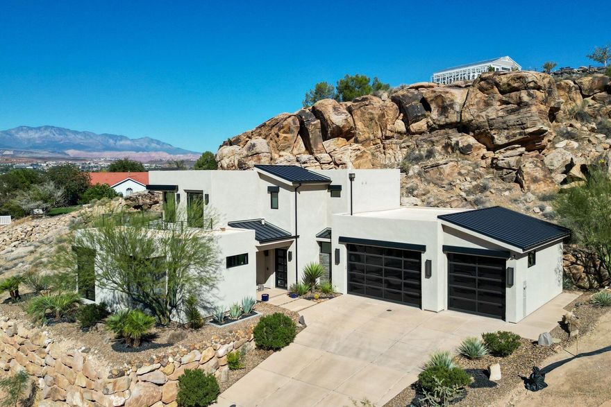 Experience modern luxury in this custom-designed masterpiece by Wayne Andersen Custom Homes, nestled on a rare 1.02-acre lot with jaw-dropping mountain views and direct access to ancient Indian petroglyphs etched into the natural rock formations behind the home—right on your property. Step through the dramatic steel-and-glass front door into a light-filled interior boasting large format porcelain tile, expansive metal-framed windows that capture the stunning surroundings, and a floating wood and metal staircase. Built with quality and longevity in mind, this home features 2x6 construction and blown-in insulation, ensuring enhanced energy efficiency and year-round comfort. The chef's kitchen impresses with high-end Bosch appliances (including a microwave drawer and refrigerator), a waterfall-edge Bianco Antico granite island, Arctic White quartz countertops, gray glass subway tile backsplash, and rich horizontal-grain cabinetry. Overhead, open beams and sleek steel elements lend a modern yet warm aesthetic. The open-concept living area features a contemporary tile gas fireplace, a recessed TV niche, and is wired for sound with indoor and outdoor speakersperfect for entertaining or relaxing to your favorite music. Even better, all audio equipment is included, offering a truly turnkey experience for media lovers. The primary suite is a private sanctuary, thoughtfully designed to maximize comfort, style, and connection to the stunning natural landscape. Wake up each morning to panoramic views of dramatic red rock formations and surrounding mountains, visible through expansive windows and from your spacious private patiothe perfect spot to enjoy coffee at sunrise or unwind under the stars. Inside, the suite showcases premium finishes and modern touches, including a custom walk-in closet with built-in drawers and shelving for effortless organization. The spa-inspired en suite bathroom features a sleek double sink vanity, designer fixtures, and a luxurious walk-through shower with dual shower-headsoffering both elegance and functionality. The guest en-suite also includes a spa-like bathroom with double sink vanity, walk-in shower, built-in closet shelving, and stunning views from the room. Outside, the xeriscaped backyard is an entertainer's dream, featuring a custom sauna, a built-in Char-Broil BBQ, a cozy fire pit, and solar-powered landscape lighting. Relax and explore your private outdoor space with natural boulders and red rock cliffs as your backdrop. The oversized garage features epoxy-coated floors, tinted glass & metal doors, and extra-tall ceilingsperfect for storing recreational equipment, vehicles, or setting up a workshop. 

Located in a secure gated community, this home is ideally positioned within a short distance to the following trails: Radio Tower trail, Kentucky Lucky Chicken trail, and trailhead for the Virgin River bike path. The home is a short drive from the towering cliffs of Zion National Park, the hoodoos of Bryce Canyon, Snow Canyon State Park and the North Rim of the Grand Canyon. Explore world-class hiking, mountain biking, and water-sports at four nearby reservoirs. The region is also known for its internationally renowned golf courses that have hosted the PGA tournament and the LPGA. Saint George is also the host for many events such as the Ironman, Red Bull Rampage, The Huntsman Senior Games and the Saint George Marathon. 

All information provided is reliable but not guaranteed. The buyer is responsible for verifying all listing details, including square footage and acreage, to their own satisfaction.