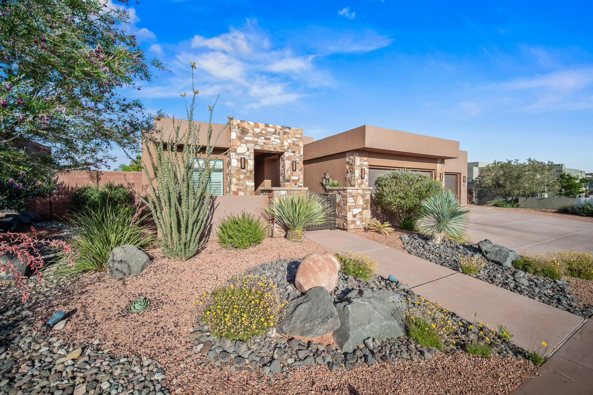 This truly beautiful and luxurious home offers quality and comfort inside and out, highlighted by expansive windows framing stunning views of Red Mountain, and, an incredible private oversized backyard retreat. Crafted with solid, superior construction rarely found in today's builds, the home is filled with upgraded trim, finishes, and features throughout. Step inside to lofty ceilings, 10-foot plate with elevated heights of 11 feet in the kitchen, 12 feet in the entry, office, and great room, and soaring to 15 feet on the exterior. Beautiful faux-wood floor tile, decorative shower and backsplash tiles, quartz countertops, quality blinds and plantation shutters, high-end appliances with double ovens, gas range and custom hood, all reflect the attention to detail. Cont'd... The kitchen offers 2 walk-in pantries - storage is abundant throughout with well-designed closets, cabinets and nooks. A dual-zone HVAC system helps with heating and AC efficiency. And even the insulation is top-tier, with superior protection in external walls and interior sound walls thoughtfully built for comfort.
The backyard is a showpiece of its own, offering tall covered patios with oversized columns and decorative trellis, a complete outdoor kitchen with grill, pizza oven, and cooking station, and a rooftop lounge accessed by an elegant circular staircase. Relax in the hot tub surrounded by attractive decking, or meander through flagstone walkways, manicured lawns, gardens, and peaceful sitting areas. Auto-accent lighting bathes the area in ambient light at night. Also, for the green thumb, there are vegetable garden boxes, and mature plum and pomegranate trees. RV parking w/full hook-ups rests behind custom iron-work gates. Bonus spaces include a garage office and art studio, and even a decorative potting shed or hobby room, just a few of the countless extras that make this home truly exceptional.