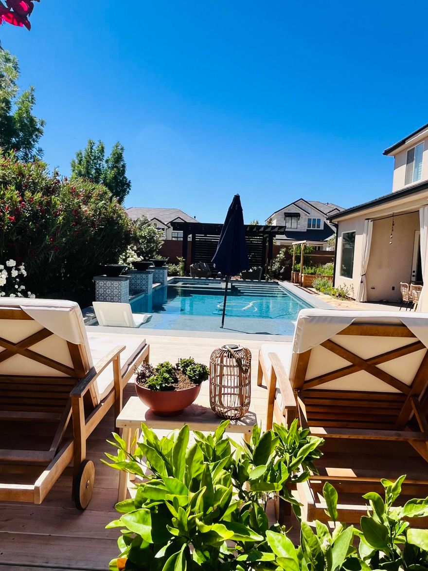 Mediterranean resort style backyard, on a corner lot. Luxury Home! Over $200,000 in Premium Upgrades This stunning home showcases over $200,000 in premium upgrades and offers the perfect blend of luxury, privacy, and functionality on a fully landscaped corner lot with a gated yard. Enjoy resort-style outdoor living featuring a saltwater pool with lit waterfalls and fire bowls, a high-end ACCOYA wood pool deck, and low-maintenance Mediterranean landscaping with flagstone pathways. The pergola is stubbed with gas for a future outdoor fireplace or kitchen, and the large covered patio creates the ultimate entertaining space. A custom metal driveway ramp accommodates low-profile
vehicles. Inside, you'll find hardwood floors throughout, quartz countertops, white oak cabinetry, and a fireplace with built-in shelving. The primary suite features a custom 8-ft frameless glass shower door, and motorized shades add convenience in the primary bedroom, living room, kitchen dining area, and upstairs family room. Tinted windows provide added privacy and energy efficiency. Additional highlights include a brand-new Bosch dishwasher, upgraded Café appliances, cedar garden grow boxes, mature fruit trees, and thoughtful upgrades throughout that make this property truly move-in ready.