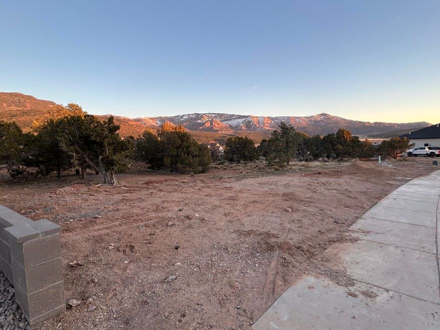 One of the last remaining view lots on Rock Ridge Rd! This great lot has views of Cedar Mountain and Shurtz Canyon for glorious sunrises & beautiful alpenglow at sunset. At 0.39 acres, it is large enough for a good-sized single-level home (no obstructed views) or whatever your family needs. All utilities are stubbed to the lot, and the lot is ready and waiting for your dream home! Block wall on one side already, and there are a few old Pinyon and Juniper trees to give the lot character. Water meter to be set at the time of building permit.