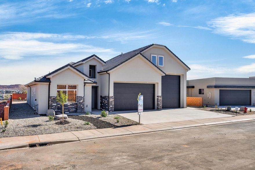 Welcome to Black Stone in beautiful Ivins, breathtaking Red Mountain backdrop. This brand-new home showcases stunning views, thoughtful design, and elevated finishes throughout. An inviting open floor plan is highlighted by luxury wood-plank flooring, both stylish and durable, perfectly suited for Southern Utah living. The kitchen is truly the heart of the home, featuring custom knotty alder cabinetry with rich natural wood grain, soft-close hardware, and detailed craftsmanship. Designer selected granite countertops pair seamlessly with a modern stacked tile backsplash and stainless-steel appliances, creating a warm space ideal for everyday living and entertaining. The spacious living room offers tall ceilings and is plumbed for a future fireplace, providing the perfect setting to gather and relax. A convenient half bath is located just off the main living area for guests. The main level includes two secondary bedrooms with a full bathroom, along with a beautifully appointed primary suite. The primary bath features sleek finishes and a spa-like atmosphere, complete with a 3/8" Euro glass shower enclosure. Upstairs, you'll find a versatile bonus room with its own full bathroom, ideal for a media room, office, gym, or private guest retreat. It is also plumbed for a mini-split system, allowing for customized climate control. Additional highlights include the entire home plumbed for central vacuum, a fully landscaped yard with room for a future pool, and exceptional garage space with a 12' wide x 14' tall RV garage door plus an oversized two-car garage with an 18' wide, 10' tall door. Offering space, quality craftsmanship, and unforgettable Red Mountain views, this home is a rare opportunity in one of Ivins' most desirable communities.