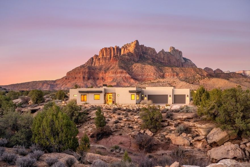 Elite Zion Retreat: Solar-Powered Luxury with Epic Outdoor Living

Welcome to 3000 Navajo Way, where luxury living meets the raw, breathtaking power of Zion National Park. This home rises from solid bedrock, surrounded by sweeping 360° views of Mt. Kinesava, Eagle Crags, and the towering sandstone cliffs that make Springdale one of the most spectacular landscapes in the American Southwest. For those who crave adventure, beauty, and a home that matches the drama of its surroundings—this is it.

Inside, bold architectural lines and natural materials set the tone: polished concrete floors, tall Alder doors, Cherrywood cabinetry, and vaulted ceilings up to 13 feet in the Great Room. The gas fireplace anchors the space, offering warmth and ambiance after long days on the trail. The chef's kitchen is built for serious culinary performance with Wolf appliances, Sub-Zero refrigeration, and striking leathered granite surfaces.

The Primary Suite offers a front-row seat to Mt. Kinesava's iconic silhouette, a true primary retreat with a steam shower, dual shower heads, and a beautifully designed walk-in closet system. A second en-suite bedroom gives guests privacy, while additional bedrooms and office space frame dramatic views of the cliffs, bridges, and a beautiful mountain wash below.

Step onto the 1,176 SF patio, your command center for outdoor living. Whether you're watching desert storms roll across the cliffs, relaxing by the firepit, or soaking in the Endless Pools Swim Spa, Bullfrog Hot Tub Spa or atop the Spectacular Rooftop Deck with 360-degree Mountain Views, the scenery here is unforgettable. Wildlife wanders past like a daily parade, quail families, soaring birds, and the natural rhythms of canyon life.

With 50 solar panels slashing electric bills to nearly nothing, a 1,144 SF 3-car garage, modern mechanical systems, and all major appliances included, this home delivers both rugged independence and refined comfort. And all of it just minutes from the world-class hikes, restaurants, and wonders of Zion National Park.

A rare opportunity to live where the power of Zion meets the warmth of true desert living.