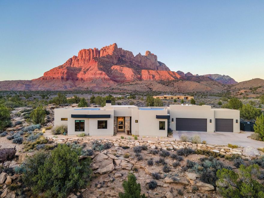 Elite Zion Retreat: Solar-Powered Luxury with Epic Outdoor Living

Welcome to 3000 Navajo Way, where luxury living meets the raw, breathtaking power of Zion National Park. This home rises from solid bedrock, surrounded by sweeping 360° views of Mt. Kinesava, Eagle Crags, and the towering sandstone cliffs that make Springdale one of the most spectacular landscapes in the American Southwest. For those who crave adventure, beauty, and a home that matches the drama of its surroundings—this is it.

Inside, bold architectural lines and natural materials set the tone: polished concrete floors, tall Alder doors, Cherrywood cabinetry, and vaulted ceilings up to 13 feet in the Great Room. The gas fireplace anchors the space, offering warmth and ambiance after long days on the trail. The chef's kitchen is built for serious culinary performance with Wolf appliances, Sub-Zero refrigeration, and striking leathered granite surfaces.

The Primary Suite offers a front-row seat to Mt. Kinesava's iconic silhouette, a true primary retreat with a steam shower, dual shower heads, and a beautifully designed walk-in closet system. A second en-suite bedroom gives guests privacy, while additional bedrooms and office space frame dramatic views of the cliffs, bridges, and a beautiful mountain wash below.

Step onto the 1,176 SF patio, your command center for outdoor living. Whether you're watching desert storms roll across the cliffs, relaxing by the firepit, or soaking in the Endless Pools Swim Spa, Bullfrog Hot Tub Spa or atop the Spectacular Rooftop Deck with 360-degree Mountain Views, the scenery here is unforgettable. Wildlife wanders past like a daily parade, quail families, soaring birds, and the natural rhythms of canyon life.

With 50 solar panels slashing electric bills to nearly nothing, a 1,144 SF 3-car garage, modern mechanical systems, and all major appliances included, this home delivers both rugged independence and refined comfort. And all of it just minutes from the world-class hikes, restaurants, and wonders of Zion National Park.

A rare opportunity to live where the power of Zion meets the warmth of true desert living.