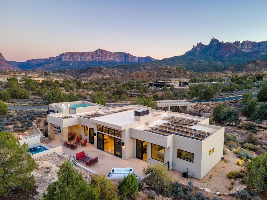 Elite Zion Retreat: Solar-Powered Luxury with Epic Outdoor Living

Welcome to 3000 Navajo Way, where luxury living meets the raw, breathtaking power of Zion National Park. This home rises from solid bedrock, surrounded by sweeping 360° views of Mt. Kinesava, Eagle Crags, and the towering sandstone cliffs that make Springdale one of the most spectacular landscapes in the American Southwest. For those who crave adventure, beauty, and a home that matches the drama of its surroundings—this is it.

Inside, bold architectural lines and natural materials set the tone: polished concrete floors, tall Alder doors, Cherrywood cabinetry, and vaulted ceilings up to 13 feet in the Great Room. The gas fireplace anchors the space, offering warmth and ambiance after long days on the trail. The chef's kitchen is built for serious culinary performance with Wolf appliances, Sub-Zero refrigeration, and striking leathered granite surfaces.

The Primary Suite offers a front-row seat to Mt. Kinesava's iconic silhouette, a true primary retreat with a steam shower, dual shower heads, and a beautifully designed walk-in closet system. A second en-suite bedroom gives guests privacy, while additional bedrooms and office space frame dramatic views of the cliffs, bridges, and a beautiful mountain wash below.

Step onto the 1,176 SF patio, your command center for outdoor living. Whether you're watching desert storms roll across the cliffs, relaxing by the firepit, or soaking in the Endless Pools Swim Spa, Bullfrog Hot Tub Spa or atop the Spectacular Rooftop Deck with 360-degree Mountain Views, the scenery here is unforgettable. Wildlife wanders past like a daily parade, quail families, soaring birds, and the natural rhythms of canyon life.

With 50 solar panels slashing electric bills to nearly nothing, a 1,144 SF 3-car garage, modern mechanical systems, and all major appliances included, this home delivers both rugged independence and refined comfort. And all of it just minutes from the world-class hikes, restaurants, and wonders of Zion National Park.

A rare opportunity to live where the power of Zion meets the warmth of true desert living.