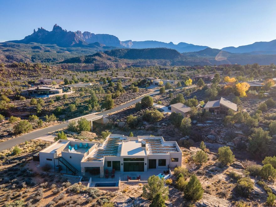 Elite Zion Retreat: Solar-Powered Luxury with Epic Outdoor Living

Welcome to 3000 Navajo Way, where luxury living meets the raw, breathtaking power of Zion National Park. This home rises from solid bedrock, surrounded by sweeping 360° views of Mt. Kinesava, Eagle Crags, and the towering sandstone cliffs that make Springdale one of the most spectacular landscapes in the American Southwest. For those who crave adventure, beauty, and a home that matches the drama of its surroundings—this is it.

Inside, bold architectural lines and natural materials set the tone: polished concrete floors, tall Alder doors, Cherrywood cabinetry, and vaulted ceilings up to 13 feet in the Great Room. The gas fireplace anchors the space, offering warmth and ambiance after long days on the trail. The chef's kitchen is built for serious culinary performance with Wolf appliances, Sub-Zero refrigeration, and striking leathered granite surfaces.

The Primary Suite offers a front-row seat to Mt. Kinesava's iconic silhouette, a true primary retreat with a steam shower, dual shower heads, and a beautifully designed walk-in closet system. A second en-suite bedroom gives guests privacy, while additional bedrooms and office space frame dramatic views of the cliffs, bridges, and a beautiful mountain wash below.

Step onto the 1,176 SF patio, your command center for outdoor living. Whether you're watching desert storms roll across the cliffs, relaxing by the firepit, or soaking in the Endless Pools Swim Spa, Bullfrog Hot Tub Spa or atop the Spectacular Rooftop Deck with 360-degree Mountain Views, the scenery here is unforgettable. Wildlife wanders past like a daily parade, quail families, soaring birds, and the natural rhythms of canyon life.

With 50 solar panels slashing electric bills to nearly nothing, a 1,144 SF 3-car garage, modern mechanical systems, and all major appliances included, this home delivers both rugged independence and refined comfort. And all of it just minutes from the world-class hikes, restaurants, and wonders of Zion National Park.

A rare opportunity to live where the power of Zion meets the warmth of true desert living.