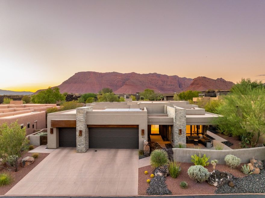 Welcome to an architectural masterpiece in The Reserve at Entrada, where modern luxury meets timeless desert beauty. This 3,000 sq. ft. residence offers 3 bedrooms, 3 bathrooms, and a 3-car garage, thoughtfully designed for both elegance and function.

Perched to capture incredible views of Red Mountain and Snow Canyon, the home invites you to relax in complete privacy, surrounded by striking landscapes and a tranquil custom water feature. Expansive glass walls and European windows and doors frame the scenery while enhancing energy efficiency, strength, and comfort.

Inside, the home showcases high-end Thermador appliances, a tankless water heater with instant hot water, and a whole-home Lutron electrical system with automated shades. Designed with durability in mind, it features steel studs, steel roof trusses, foam insulation, and geo-tech stabilization under the foundation. Comfort is elevated with 10 heating and cooling zones using mini-splits for ultimate efficiency.

Outdoor living is equally spectacular, with multiple patios, a rooftop deck, firepit, fireplace, saltwater hot tub, and solar panels providing a seamless extension of the home. Modern conveniences include a whole-house surge protector, water softener with reverse osmosis, Aqua-Air central vac, Ring security system with cameras, and two EV charging stations.

Every detail has been thoughtfully curated, from the open-concept living spaces to the luxurious finishes throughout. Whether entertaining guests or savoring quiet moments, this home captures the beauty and serenity of its surroundings, offering a lifestyle that is both elevated.