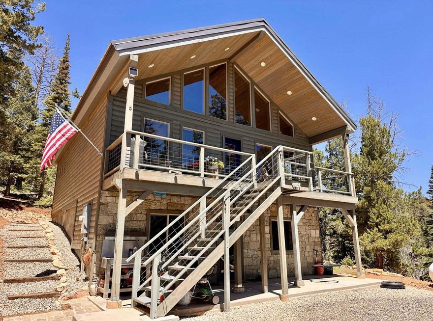 Welcome to your dream cabin in the woods—where luxury meets wilderness. This immaculate 3-bedroom, 2-bathroom home spans 2,464 sq ft and was built in 2021 with no detail spared. Tucked among majestic tall pines with breathtaking views of the nearby ski slopes, this property offers the perfect blend of modern comfort and rustic charm. Step inside to soaring ceilings, an open-concept living area, and a warm, inviting design that makes you feel right at home. The gourmet kitchen features high-end finishes and flows seamlessly into the spacious great room—ideal for hosting or cozy nights by the fire.
The oversized windows bring the outdoors in, showcasing the beauty of the surrounding forest and mountain scenery. The home's condition is truly pristine turnkey and ready for year-round liv