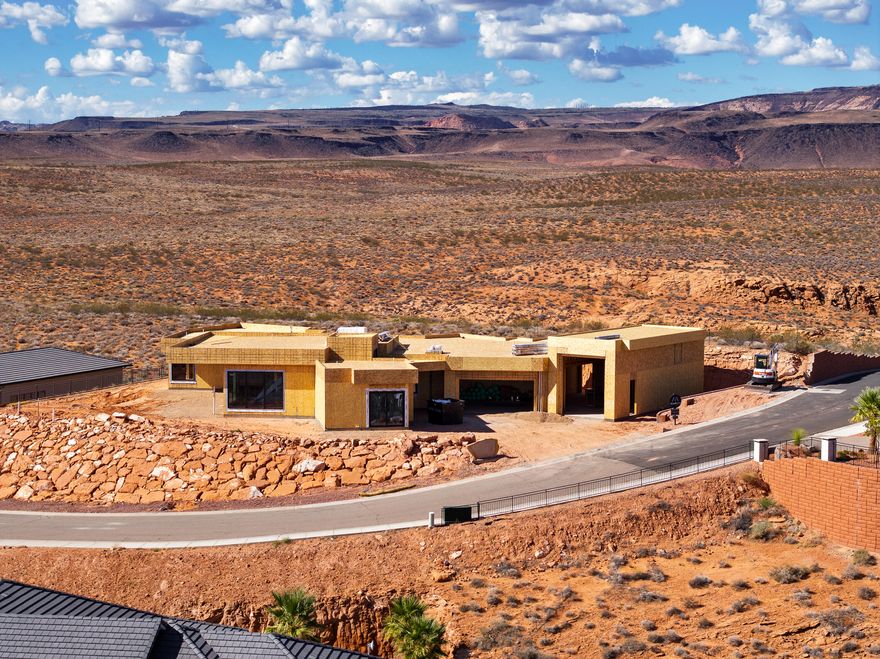 Perched near the top of the gated enclave- Westgate Hills, this single-level home takes in sweeping views of Pine Valley Mtn, sandstone cliffs, city lights & crimson ridges to the south. Set on a private ½-acre lot, it features a 43-ft RV garage w/12'x14' door, 3-car garage & RV pad. Outdoor living shines w/ heated pool, spa, waterfall feature, shamu shelf & auto cover. Inside: 5 beds (5th as office w/view), glass media room, private guest suite with incredible views, a chef's kitchen w/ custom cabinets, high-end countertops & appliances, large working pantry w/southern mountain views + an additional storage pantry. Primary retreat has a large window that perfectly captures Pine Valley Mtn views, has a spa-like bath & spacious closet w/ laundry hookups. Est. completion Jan 2026.