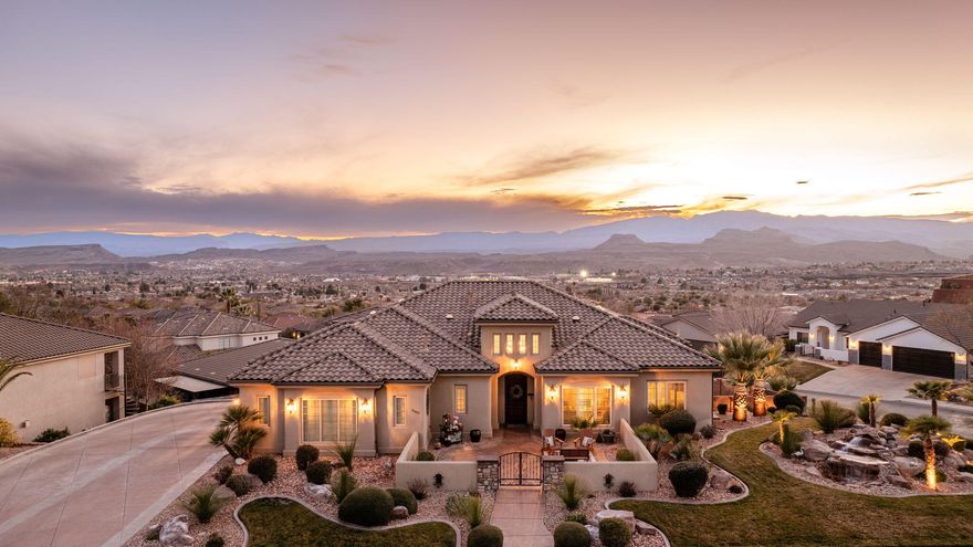 This exceptional St. George home is perched on a spacious .43-acre lot with no HOA, breathtaking views, and resort-style outdoor living. From the moment you arrive, enjoy stunning curb appeal, a private gated courtyard entry, and panoramic vistas across the valley and surrounding mountains. Inside, generous light-filled living spaces, soaring ceilings, and a warm layout are perfect for entertaining or everyday comfort. The kitchen features rich wood cabinetry, expansive counters, and an oversized island, with dining framed by view windows. Multiple living areas include a large bonus/game room with a full bar. The primary suite offers a soaking tub, dual vanities, and walk-in closet. Outside, unwind in your backyard oasis with a sparkling pool, expansive patio, and unforgettable sunsets.