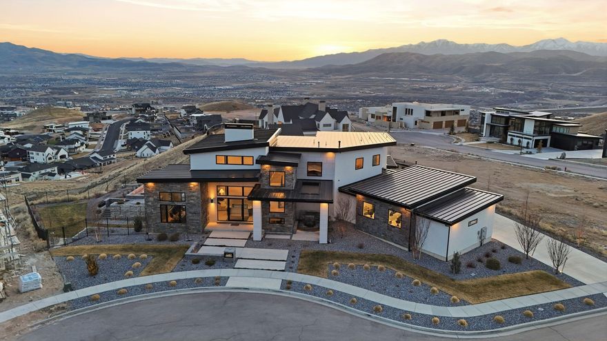 Perched above the valley with sweeping panoramic views of the lake, city lights, and surrounding mountains, this striking modern residence offers an exceptional blend of luxury design and indoor-outdoor living. Thoughtfully designed with clean architectural lines and expansive windows, the home captures breathtaking scenery from nearly every angle. The elevated setting provides privacy while showcasing unforgettable sunsets and dramatic views across the valley.The outdoor living space is truly resort-inspired. A stunning infinity-edge pool, elegant fire lounge, and multiple entertaining terraces create the perfect environment for both intimate evenings and large gatherings. The covered patio and upper balcony provide seamless transitions between indoor comfort and outdoor relaxation while overlooking the spectacular landscape. Inside, the home features modern finishes, open-concept living areas, and floor-to-ceiling glass that flood the space with natural light and frame the incredible views. The design emphasizes both sophistication and livability, offering luxurious yet comfortable spaces for everyday living. As evening falls, the property transforms into something special-twinkling city lights below and mountain silhouettes beyond create a breathtaking backdrop rarely found in residential settings. Located in a premier hillside community, this home offers a rare opportunity to enjoy elevated luxury living with unmatched views and exceptional outdoor amenities.