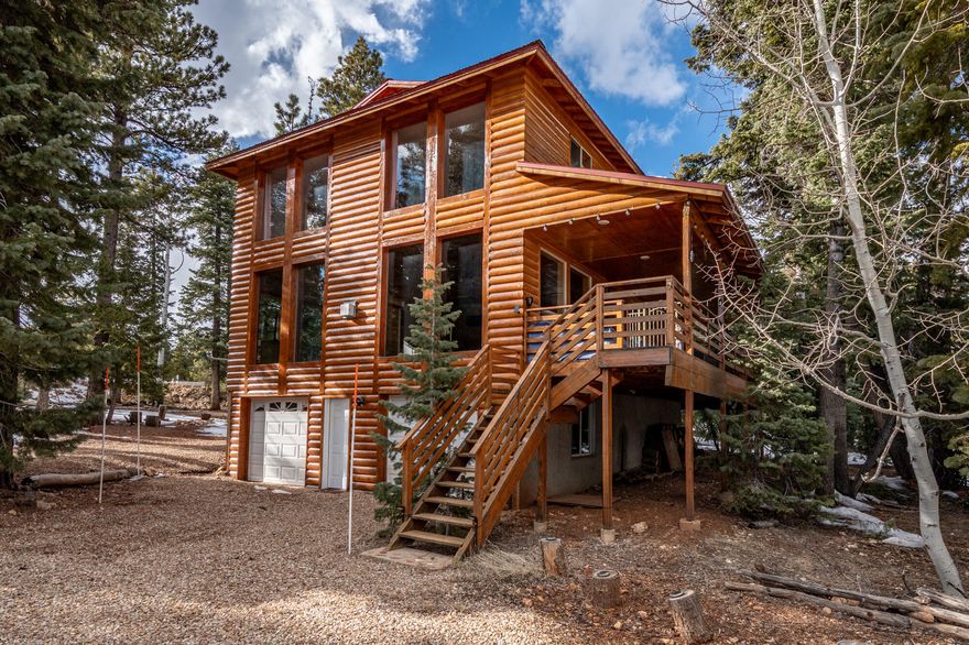 This stunning 2,706-square-foot, three-level cabin sits on just under half an acre and offers 3 bedrooms and 2.5 bathrooms in a thoughtfully designed layout. The main level features a spacious open floor plan filled with natural light from expansive windows and multiple access points to the deck—perfect for seamless indoor-outdoor living. You'll also find a convenient half bath, a beautifully modern kitchen with a walk-in pantry, and a nearby laundry room with ample storage. The upper level serves as a private primary suite, complete with a generous walk-in closet and a large ensuite bath, all surrounded by windows that create a bright, serene retreat. Downstairs, the basement level includes two additional bedrooms and a full bathroom, ideal for guests or family. Step outside to enjoy the covered deck and a spacious lot with plenty of room for a firepit and entertaining - an ideal setting for gatherings and making lasting memories.