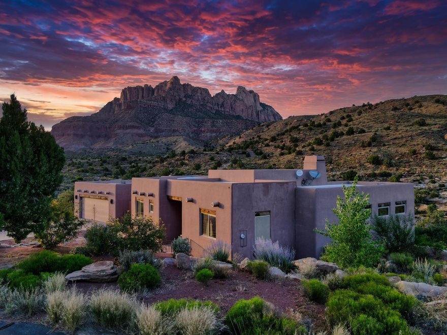 Experience elevated living in Springdale, Utah—just minutes from the entrance to Zion National Park. Nestled at the end of a private cul-de-sac, this 3-bedroom, 2-bath luxury residence is surrounded by a conservation easement, offering both privacy and the feeling of an expansive estate.

The thoughtfully designed 1,875 square feet of open living space features soaring 12-foot ceilings in the living room, elegant concrete floors, and walls of windows that frame 360-degree mountain views from sunrise to sunset. The open floor plan creates seamless flow, complemented by a chef's kitchen with granite countertops, a propane cooktop, and custom cabinetry, while an adobe-style propane fireplace adds warmth and charm. A whole-home water filtration system enhances daily comfort, and a spacious 2-car garage with storage provides practical functionality.

Step outside to savor the landscape: a beautifully landscaped property, an expansive back deck ideal for entertaining, quiet mornings, or evenings beneath the desert sky. Every corner of this home whispers of thoughtful design and lasting quality.

Here, mornings awaken with mountain light, evenings linger on the deck in the desert breeze, and nights sparkle with infinite stars. Just minutes from Zion National Park, and within reach of Bryce Canyon, Coral Pink Sand Dunes, the North Rim of the Grand Canyon, Sand Hollow, Snow Canyon, and St. George, this is not just a residence, it is an invitation to live in harmony with the land's most majestic wonders.