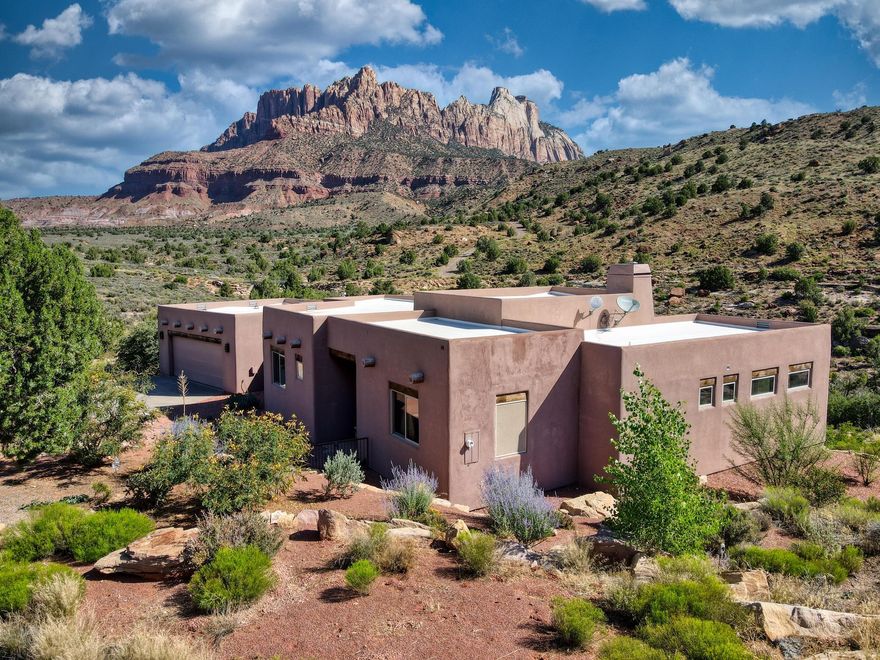 Experience elevated living in Springdale, Utah—just minutes from the entrance to Zion National Park. Nestled at the end of a private cul-de-sac, this 3-bedroom, 2-bath luxury residence is surrounded by a conservation easement, offering both privacy and the feeling of an expansive estate.

The thoughtfully designed 1,875 square feet of open living space features soaring 12-foot ceilings in the living room, elegant concrete floors, and walls of windows that frame 360-degree mountain views from sunrise to sunset. The open floor plan creates seamless flow, complemented by a chef's kitchen with granite countertops, a propane cooktop, and custom cabinetry, while an adobe-style propane fireplace adds warmth and charm. A whole-home water filtration system enhances daily comfort, and a spacious 2-car garage with storage provides practical functionality.

Step outside to savor the landscape: a beautifully landscaped property, an expansive back deck ideal for entertaining, quiet mornings, or evenings beneath the desert sky. Every corner of this home whispers of thoughtful design and lasting quality.

Here, mornings awaken with mountain light, evenings linger on the deck in the desert breeze, and nights sparkle with infinite stars. Just minutes from Zion National Park, and within reach of Bryce Canyon, Coral Pink Sand Dunes, the North Rim of the Grand Canyon, Sand Hollow, Snow Canyon, and St. George, this is not just a residence, it is an invitation to live in harmony with the land's most majestic wonders.