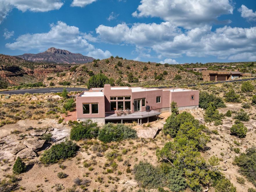 Experience elevated living in Springdale, Utah—just minutes from the entrance to Zion National Park. Nestled at the end of a private cul-de-sac, this 3-bedroom, 2-bath luxury residence is surrounded by a conservation easement, offering both privacy and the feeling of an expansive estate.

The thoughtfully designed 1,875 square feet of open living space features soaring 12-foot ceilings in the living room, elegant concrete floors, and walls of windows that frame 360-degree mountain views from sunrise to sunset. The open floor plan creates seamless flow, complemented by a chef's kitchen with granite countertops, a propane cooktop, and custom cabinetry, while an adobe-style propane fireplace adds warmth and charm. A whole-home water filtration system enhances daily comfort, and a spacious 2-car garage with storage provides practical functionality.

Step outside to savor the landscape: a beautifully landscaped property, an expansive back deck ideal for entertaining, quiet mornings, or evenings beneath the desert sky. Every corner of this home whispers of thoughtful design and lasting quality.

Here, mornings awaken with mountain light, evenings linger on the deck in the desert breeze, and nights sparkle with infinite stars. Just minutes from Zion National Park, and within reach of Bryce Canyon, Coral Pink Sand Dunes, the North Rim of the Grand Canyon, Sand Hollow, Snow Canyon, and St. George, this is not just a residence, it is an invitation to live in harmony with the land's most majestic wonders.