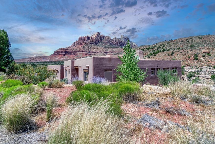 Experience elevated living in Springdale, Utah—just minutes from the entrance to Zion National Park. Nestled at the end of a private cul-de-sac, this 3-bedroom, 2-bath luxury residence is surrounded by a conservation easement, offering both privacy and the feeling of an expansive estate.

The thoughtfully designed 1,875 square feet of open living space features soaring 12-foot ceilings in the living room, elegant concrete floors, and walls of windows that frame 360-degree mountain views from sunrise to sunset. The open floor plan creates seamless flow, complemented by a chef's kitchen with granite countertops, a propane cooktop, and custom cabinetry, while an adobe-style propane fireplace adds warmth and charm. A whole-home water filtration system enhances daily comfort, and a spacious 2-car garage with storage provides practical functionality.

Step outside to savor the landscape: a beautifully landscaped property, an expansive back deck ideal for entertaining, quiet mornings, or evenings beneath the desert sky. Every corner of this home whispers of thoughtful design and lasting quality.

Here, mornings awaken with mountain light, evenings linger on the deck in the desert breeze, and nights sparkle with infinite stars. Just minutes from Zion National Park, and within reach of Bryce Canyon, Coral Pink Sand Dunes, the North Rim of the Grand Canyon, Sand Hollow, Snow Canyon, and St. George, this is not just a residence, it is an invitation to live in harmony with the land's most majestic wonders.