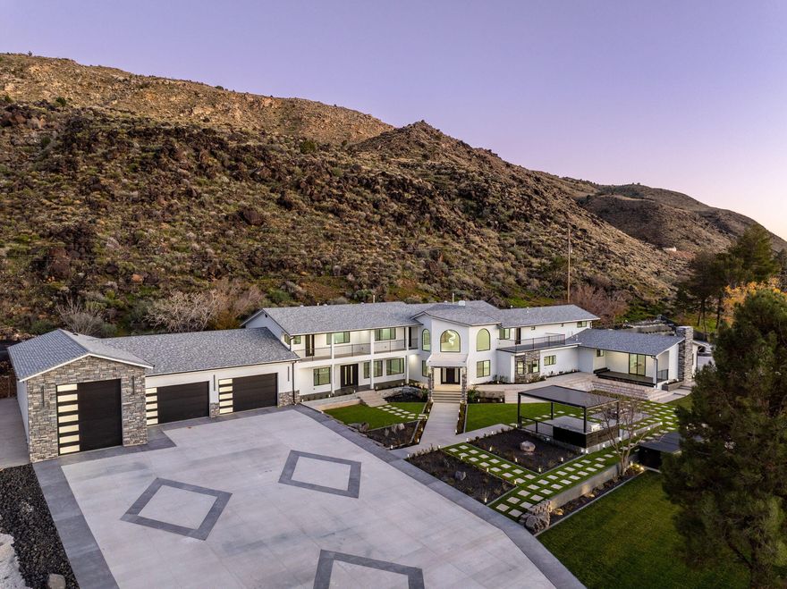 Set against a dramatic mountainside and protected by an additional parcel that preserves your views indefinitely, this one-of-a-kind estate delivers a rare combination of privacy, scale, and lasting value. Rebuilt from the ground up with over $1.2M invested into design, structure, and systems, the home offers a level of quality and intention that is immediately apparent. From the moment you arrive, the architecture makes a statement, clean modern lines, a grand entry, and soaring ceilings that create a sense of openness and light throughout the home.
Inside, never before lived in living spaces are framed by oversized windows that pull the natural landscape into every room. The finishes strike a balance between contemporary elegance and livable comfort, with large-format flooring, custom lighting, and thoughtfully designed gathering areas that flow seamlessly from one space to the next. At the center of the home, the kitchen was designed to perform as beautifully as it looks. A bold waterfall island anchors the space, complemented by full slab surfaces, professional-grade appliances, dual ovens and dishwashers, and an oversized refrigeration setup. Whether hosting large gatherings or everyday living, the layout supports both function and presentation. A walk-in pantry, custom cabinetry, and integrated bar area complete the space.
The home offers six spacious en-suite bedrooms, including a fully independent casita designed for flexibility. Each suite is finished with its own distinct character, featuring custom built-ins and refined, spa-like bathrooms. The casita operates as a true extension of the home, with its own kitchen, living space, entrance, and climate control, making it ideal for guests, extended family, or premium rental use. Additional living space is found in the finished lower level, offering the opportunity to create a theater, fitness studio, wine room, or entertainment area tailored to your needs. Outside, the property transitions into a private resort environment. Multiple gathering spaces, a covered pavilion, water features, and fire elements are positioned to take full advantage of the surrounding views. A premium swim spa and carefully designed landscaping complete an outdoor setting built equally for relaxation and entertaining. For those needing space beyond the home itself, the brand-new approximately 2,700 square foot garage delivers exceptional utility, with oversized doors, an RV bay, and room for collections, storage, or workshop use. Behind the design, the infrastructure has been fully modernized, including a 400-amp electrical system, complete rewire, new plumbing and sewer systems, multi-zone HVAC, tankless water heating, and high-efficiency insulation throughout. This is a property built not just for today, but for long-term performance and peace of mind.
Positioned minutes from major access routes and some of Southern Utah's most sought-after destinations, including Zion National Park and Sand Hollow Reservoir, the home offers both convenience and connection to the surrounding landscape.
This is more than a renovation, it is a complete rethinking of what this property could be, delivering scale, privacy, and design in a way that is increasingly difficult to replicate.