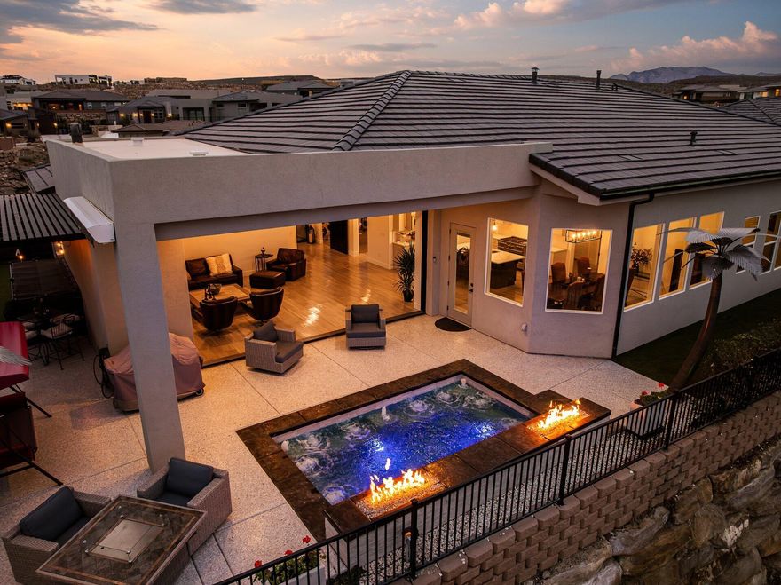THIS IS THE LIFE! Exquisite luxury residence seamlessly blends contemporary elegance with modern sophistication. Situated above the renowned Sunbrook Golf Course, it offers breathtaking, unobstructed panoramic views of red rock formations, desert landscapes, and majestic mountain horizons. Enter through grand double iron-and-glass doors, accented by designer lighting, into a bright, open main living area. A dramatic 10' × 20' disappearing glass wall glides into its hidden pocket, effortlessly merging the great room with the resort-style backyard--creating a true open-air pavilion experience. The chef's gourmet kitchen features premium Café appliances and sleek quartz countertops, perfect for everyday living and entertaining. The indulgent primary suite includes a meticulously designed walk-in closet with custom jewelry cabinetry, drawers, shelving, and racks, plus a spa-inspired bath with a separate garden tub, full-height glass shower with elegant tile-work, and motorized blinds throughout the bedrooms and primary bath. Key refinements include an oversized custom barn door, ceiling fans in all bedrooms, large-scale fans in the family room and patio, and a whole-home water softening system. The entertainer's backyard is a private oasis: custom pool with integrated jetted hot tub, dual fire pits, underwater illumination, sheer-descent waterfall, and unique metal palm tree accents. Mediterranean-inspired planters feature boxwoods, iceberg roses, palms, and hundreds of complementary plants. Low-maintenance artificial turf covers the front, back, and sides, complete with a private 3-hole putting green. Enjoy year-round outdoor living under a powered retractable awning and metal patio cover on one side, with a golf cart carport and fully enclosed custom dog run on the other. The fully fenced grounds include steel and composite gates and fencing, plus a full-height block wall for privacy and security. The oversized garage is a gear enthusiast's dream, featuring epoxy floors, RV/boat parking capability, a full wall of New Age Pro Series lockers, toolboxes, heavy-duty racks, a 4-post car lift, and mini-split AC/heating. Additional enhancements include a custom front-yard water feature, level-tiered front yard with raised planters and seating, custom concrete steps and sidewalk with integrated step lighting, and premium concrete finishes on the driveway, patios, and side yards. More than a home, this is a private desert sanctuary where sophisticated design meets effortless luxury living framed by championship golf and iconic Southern Utah vistas. Welcome to elevated modern elegance.