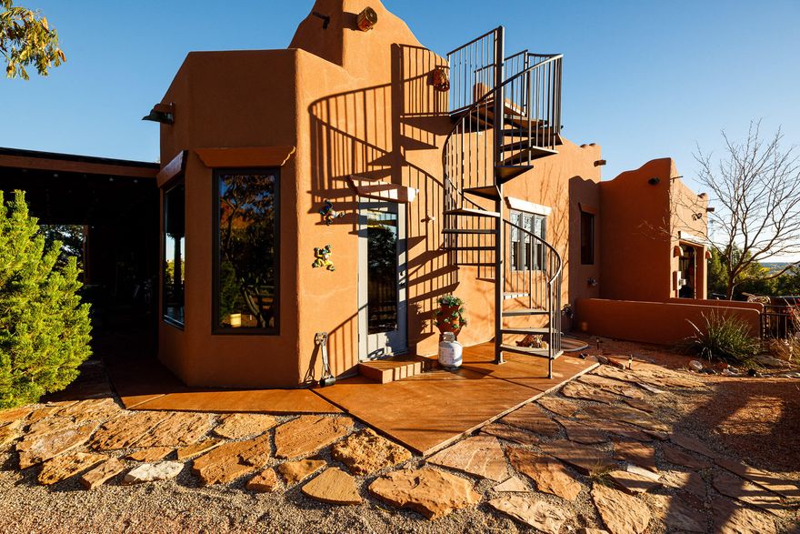 Step inside and feel the warmth of Southwest design - custom tile floors, imported sinks, and log timbers accenting the tall ceilings. A river rock fireplace anchors the spacious living area, while large sliding doors open to a private, covered patio perfect for quiet mornings or evening gatherings. The unique kitchen features a large island with bar seating and connects seamlessly to a sun-drenched dining area ideal for entertaining. The 3-bedroom, 2-bath layout features a large peaceful primary suite with its own bath and direct patio access and views that make every sunrise feel magical. Downstairs, you'll find a partially finished basement with one bedroom already framed in, offering room to expand or customize to your vision. A spiral staircase leads to the rooftop deck - your front- row seat to unforgettable sunsets and clear desert night skies. Set at the back of a 2.24-acre lot, this home sits high for unobstructed views of the red cliffs and the Kaibab Mountain range - a dream for anyone who loves the ever-changing desert light. Experience the artistry and serenity of true Southwest living in this one-of-a-kind Santa Fe masterpiece. Buyer to Verify all details.