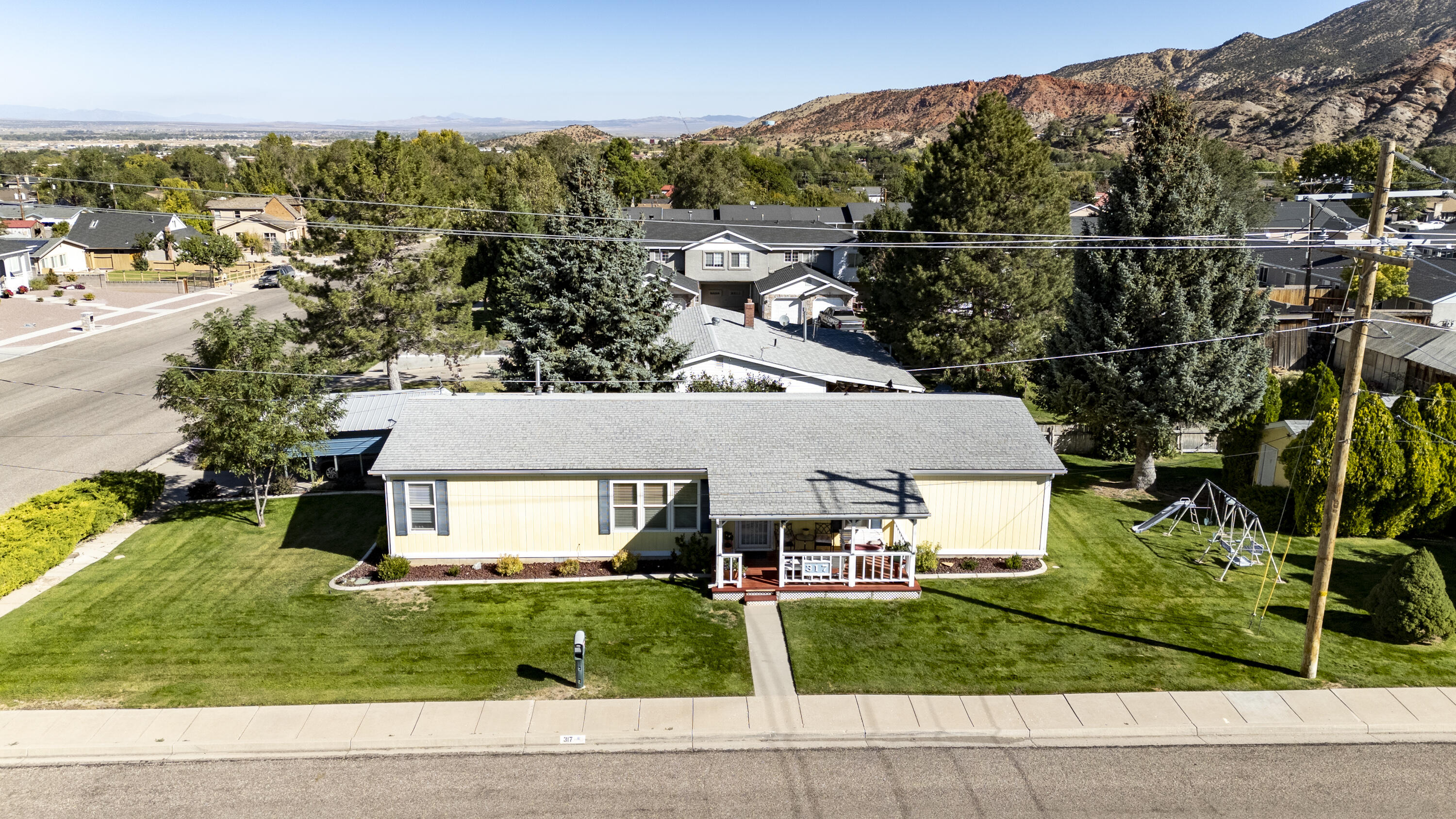 This charming manufactured home features a welcoming front porch with stunning mountain views. Inside has 3 bedrooms, an office and 2 bathrooms. The landscaped corner lot combines open space with cozy areas, perfect for gardening and enjoying a quiet neighborhood.