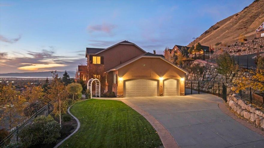 Nestled in a quiet, upscale mountainside community, this stunning 6-bedroom, 5-bath home offers breathtaking views, elegant design, and modern comfort. The open-concept floor plan features vaulted ceilings, a floor-to-ceiling stone fireplace, and expansive windows that fill the living space with natural light. The gourmet kitchen includes premium cabinetry, stainless steel appliances, and ample counter space-perfect for everyday living and entertaining. The spacious primary suite provides a private retreat with spa-like finishes and serene hillside views. Enjoy outdoor living with multiple patios, landscaped terraces for gardening, and a private yard surrounded by stone retaining walls. Sellers are master gardeners and created a paradise of fruit trees, cascading grape vines, gardening boxes and more. The large three-car garage has insulated doors, epoxy flooring, and generous storage and parking. Located minutes from local schools, parks, and shopping, this home combines peaceful hillside living with convenient city access. Seller is including the movable shed, safe in basement, small fridge in pantry, TV's and mounts, 7.2 surround system and projector in the theater room, pool table, hot tub and Covana. All items are included "as is". Home has a radon mitigation system, google fiber up to 8 gig, wifi controlled sprinkler system, and Potassium water filtration system with Trojanuvmax water purification. New flooring, paint and dishwasher! Square footage figures are provided as a courtesy estimate only and were obtained from the Assessors . Buyer is advised to obtain an independent measurement.