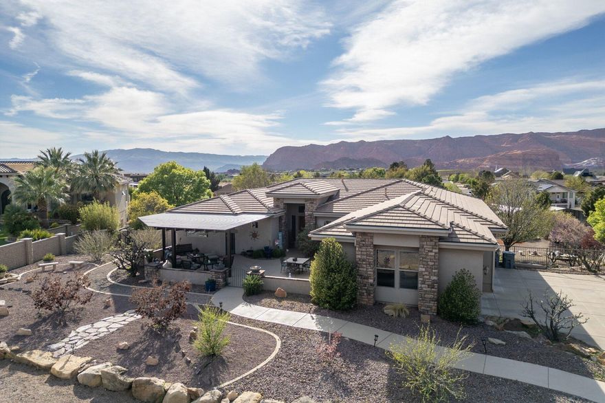 Tucked away on a fully fenced and beautifully landscaped .94 acres, this custom home blends comfort, creativity, and self-sufficiency--set against breathtaking panoramic views of the Snow Canyon State Park mountains. The property includes a 50-vine, wine-producing vineyard and two greenhouses: a 9×12 hydroponic house and a 20×42 greenhouse with raised garden beds, creating a private, vineyard-style setting with the ability to grow year-round.

Outdoor living is a true sanctuary here. Enjoy a 900 sq. ft. covered upper deck and an additional 900 sq. ft. of covered patio space on the lower level, offering endless room for entertaining or quiet retreat. A newly added front-courtyard pergola and multiple seating areas invite you to relax in every season. Start your mornings--or unwind at sunset--in the large Hot Springs hot tub, thoughtfully positioned to maximize both views and privacy.

The acreage offers exceptional versatility: continue the vineyard, expand your garden, or reimagine the space with a shop, pool, or even horses. The possibilities are wide open.

Inside, the home features 4 bedrooms, two living areas, and a dedicated art studio or workshop--ideal for creators, hobbyists, or anyone needing flexible space. An oversized garage provides abundant room for tools, equipment, or recreational gear.
A rare opportunity to enjoy a sustainable, lifestyle-driven property with views that inspire every day.