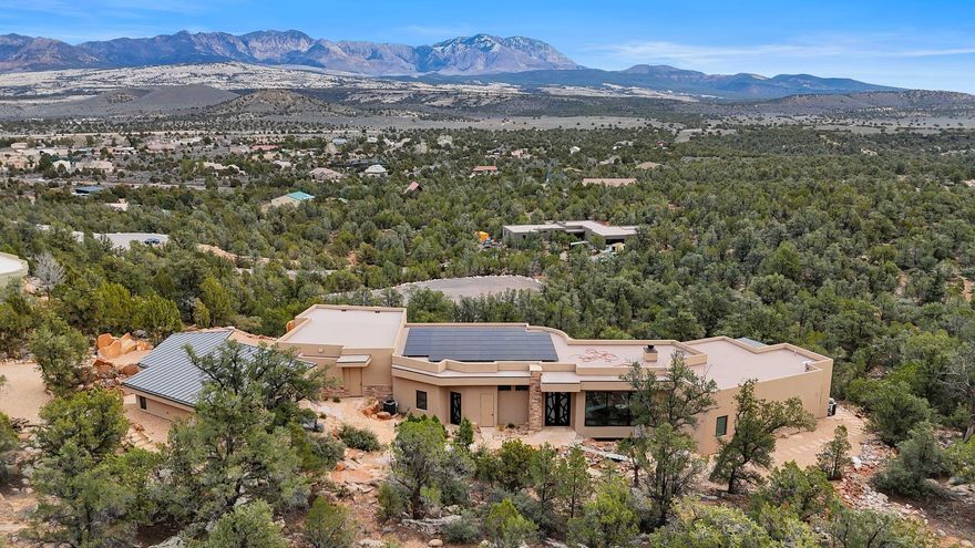 Nestled along coveted Pinion Hills Drive in Dammeron Valley, this extraordinary 2025 custom masterpiece is a rare fusion of modern luxury, self-sufficient resilience, and untouched natural splendor—truly one-of-a-kind in southern Utah. Perched at 4,700 feet on one of the larger lots in Pinion Hills (1.25 acres) and bordering vast BLM land to the south, it offers unparalleled privacy, direct access to wilderness trails, and forever-protected panoramic views of majestic Pine Valley Mountain rising to 10,500 feet. The 3,553 sq ft main residence (over 4,300 sq ft total livable including basement) is artfully designed to harmonize with its dramatic surroundings, with floor-to-ceiling windows framing breathtaking vistas from nearly every room. Sun-drenched expansive living spaces flow seamlessly into a showpiece custom kitchen, where elevated craftsmanship and intentional details create an inviting heart for gathering amid sweeping red rock landscapes.
Descending to the fully finished approx. 1,000 sq ft fortified basementa true bunker-style retreat with one-foot-thick concrete walls and ceilingyou'll find a complete secondary living suite: full kitchen, bathroom with shower, pantry, living area, reinforced safe doors, and pre-planned space for a future elevator, blending ultimate security with versatile long-term livability.
Sustainability meets sophistication with a 100% off-grid solar system featuring redundant battery backups and a 5,000-gallon underground cistern for water independencemodern resilience in an elegant package. An oversized three-car garage provides ample storage, while a detached ~700 sq ft casita offers fully equipped independent living quarters (kitchen, bath, washer/dryer), perfect for guests, rental income, or a private sanctuary.
The home's signature enchantment is its custom cascading water feature, woven into the natural topography and flowing beneath the residencea soothing symphony of sound that infuses serene, resort-like tranquility throughout, an extraordinarily rare sensory experience in custom builds.
Fully furnished and turnkey ready, this singular estatenew construction, boundless privacy, and thoughtful innovationstands alone as an irreplaceable haven in Dammeron Valley's most sought-after enclave. Seize this exceptional opportunity to claim a legacy property where adventure, elegance, and enduring beauty converge.
