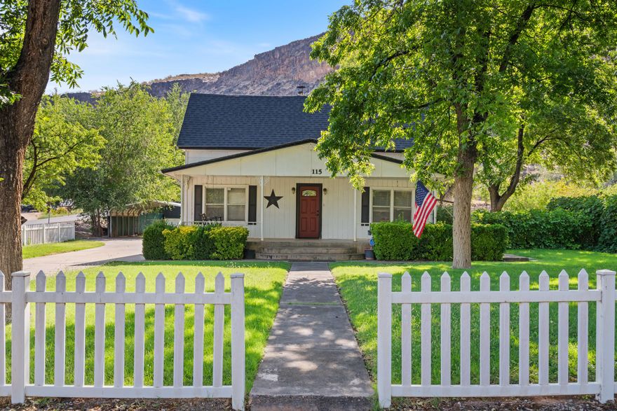So darn cute and welcoming, this vintage charmer sits steps from downtown Hurricane (shops, restaurants, all the happenings) and just 30 min from Zion. A white picket fence, mature shade trees, and a front porch with a swing set the tone. Inside, it's peak 1929 with built-ins galore, fun sloped ceilings upstairs that follow the roofline, and wood-burning stove. The kitchen packs plenty of storage, the driveway is nice and long with loads of parking plus a covered carport, and the oversized yard brings the fun with a firepit, a shed, and an additional outbuilding for your projects or storage (buyer to verify). Practical wins, too: roof is under five years old and the A/C was new in 2021. Near schools, mature landscaping, and that classic small-town vibe - welcome home to Hurricane.