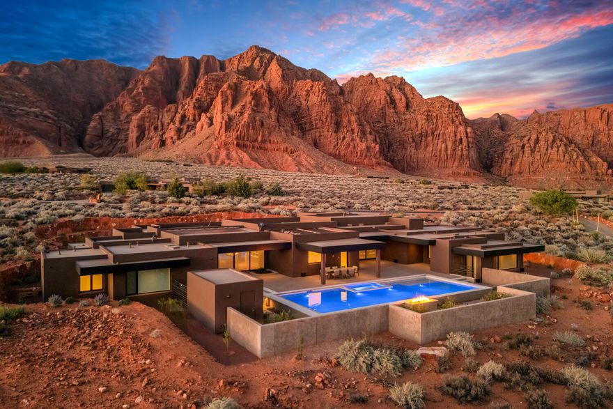As seen in Architectural Digest, this design-forward desert residence is set against the breathtaking red cliffs of Kayenta, where contemporary architecture and the surrounding landscape exist in quiet harmony. Interior design by KSA Design Group in Chicago brings a refined sensibility to every space, creating a residence that feels both sophisticated and deeply connected to the natural beauty that surrounds it. 

Expansive walls of glass frame the ever-changing colors of the desert sky and sandstone cliffs, blurring the boundary between indoors and out. Clean architectural lines, organic materials, and a restrained natural palette create interiors that feel calm, grounded, and quietly elegant. 

At the heart of the residence, the thoughtfully designed living room - showcased in Architectural Digest - features a striking tiled fireplace wall inspired by the surrounding desert landscape. Rich textures and a nuanced green glaze echo the tones of the cliffs and vegetation beyond the expansive window wall, creating a dramatic focal point that brings the beauty of the desert directly into the interior. 

Designed for both connection and retreat, the open layout flows naturally between gathering spaces and private areas. Mornings begin with coffee as the rising sun washes the red cliffs in warm light, while evenings invite conversation beside the fire as the desert sky deepens overhead. The spa-inspired primary suite includes a dedicated yoga and exercise studio, creating a serene setting for wellness and restoration, while two ensuite guest rooms and a separate lounge provide comfortable accommodations for friends and family. 

Technology is seamlessly integrated throughout the residence. Savant home automation and Lutron lighting and shading systems allow lighting, climate, audio, security, and privacy to adjust effortlessly to your preferences, while automated shades and adaptive lighting work in harmony with natural daylight throughout the day. A Tier 1 solar system further supports efficient and sustainable living. 

Outdoor living is equally compelling. Expansive patios, a sparkling pool with integrated hot tub, and a dramatic fire feature create inviting spaces to gather, entertain, or simply unwind beneath the vast desert sky. Whether enjoying a quiet morning swim or hosting friends as the desert landscape shifts through sunset colors, the setting offers a rare sense of tranquility and connection to nature. 

A modern desert sanctuary, this residence brings together thoughtful architecture, refined design, and the timeless beauty of Kayenta to create a home that feels both elevated and deeply restorative.