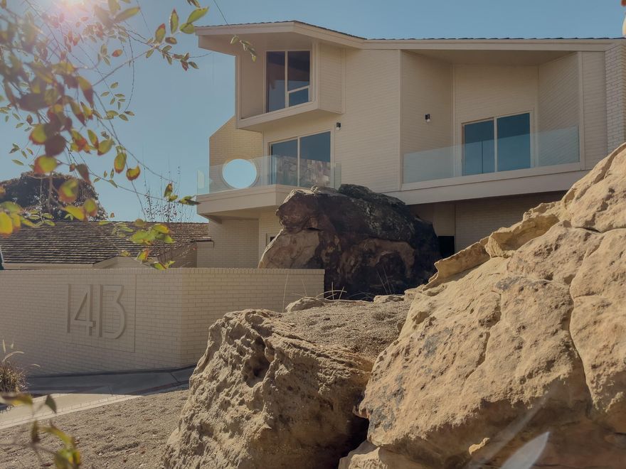 Set against the striking backdrop of the Bloomington Bluff, House No. 1413 is a rare architectural residence where postmodern artistry meets the serenity of the Southern Utah desert. Originally designed in 1982 by architect Thomas A. Dobrusky and thoughtfully reimagined in 2025 by designer Emily Barnas, offering a refined balance of bold expression and quiet luxury.

Beyond the custom stained glass entry, the home unfolds through sculptural geometry, soaring wood ceilings, and transom windows that bathe the interiors in soft desert light. Massive natural boulders anchor the home's core, creating a powerful connection between architecture and landscape, while cedar warmth, hand-finished details, and two wood-burning fireplaces add depth and intimacy throughout.

At the heart of the residence, a dramatic indoor saltwater pool and spa curve gracefully around a twenty-foot natural boulder centerpiece. Skylights, cedar ceilings, and glass railings flood the space with light, while reimagined circulation and multi-level vantage points make the architecture feel dynamic yet effortless, an experience that is as immersive as it is livable.

The comprehensive 2025 renovation renewed nearly every surface with a material-forward approach. A sculptural Calacatta marble kitchen with high-end appliances anchors the living spaces, while spa-inspired bathrooms feature Zellige tile, Cantera stone, Kohler fixtures, and artisan finishes. Redwood hardwood floors and curated designer lighting elevate the home throughout, blending modern refinement with organic warmth.

A private wellness retreat offers a dry sauna, steam room, and cold plunge, transforming daily routines into restorative rituals. Expansive indoor-outdoor connections create an effortless flow for entertaining, while geothermal heating and cooling ensure year-round comfort with modern efficiency.

Set on low-maintenance grounds with no HOA, the home captures sweeping views of Pine Valley Mountain, Gooseberry Mesa, and the Arizona Strip. Conveniently located near schools, shopping, and golf courses, House No. 1413 offers a rare balance of architectural significance, livable luxury, and lifestyle accessibility. Both art and refuge, this residence invites you to live boldly while resting deeply.