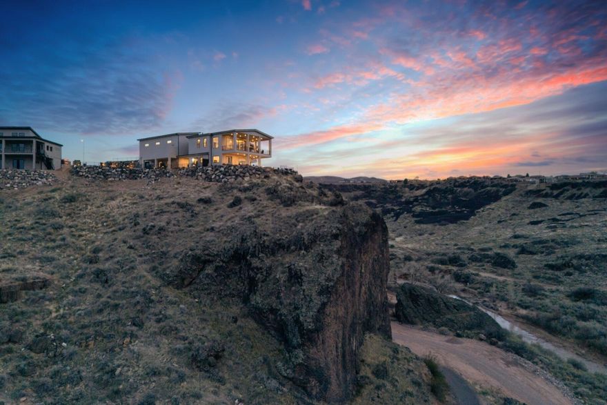 This remarkable home offers much more than meets the eye, providing a truly unique living experience. Nestled above the stunning Confluence Park protected by the Red Cliffs Desert Reserve, with direct access to hiking trails right out your back door. An Anasazi cave once occupied by Paiute and Anasazi Indians is an historical treasure right on this property. This custom-designed home boasts breathtaking 270-degree unimpeded views from its unique perch atop a peninsula basalt cliff. Borders protected lands w/hiking trails outside your door, stunning panoramas of the Virgin River, a dramatic volcanic gorge, and inspiring Pine Valley Mtns. Garage Capacity noted as 12 includes the RV garage. The main level provides seamless living with a spacious primary ensuite, a guest bedroom, an office, and an expansive kitchen, dining, and living area-perfect for both relaxation and entertaining. Sliding doors and windows open up to a covered patio, allowing you to take in the awe-inspiring natural landscape and views.

The walkout basement adds even more value with private bedrooms, a kitchenette, a bar, a cozy den, ample entertainment space, and plenty of storage. Outside, the resort-style backyard with a refreshing pool and an outdoor fireplace offers the ultimate in fun and relaxation. For those seeking additional income, this property includes three separate casitas for hosting guests OR could be used for a nightly rental business if it is your primary residence.  

To top it all off, this estate features extensive storage, a 20'x50' RV garage with a 14'x14' door, and a huge workshop space-ideal for all your hobbies and projects. Multiple garages could be used for boats and other toys or LOTS of cars.