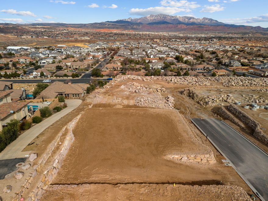 Panoramic views to the North East of surrounding mountains and the city lights, resting on top of the prestigious gated community of Stone Cliff. Resort-style amenities include clubhouse, new event center, fitness with new equipment, indoor/outdoor pool & spa, cabanas, fitness center, tennis/pickle-ball courts, 24/7 security. 1st year, the monthly HOA fee for a developer lot is 1/3rd of current monthly HOA fee ($344 currently) which is $121 per month, full monthly HOA fee after the 1st year.  Low Utilities with Dixie Power, Buyer is responsible for Washington County Water Conservancy impact fee.