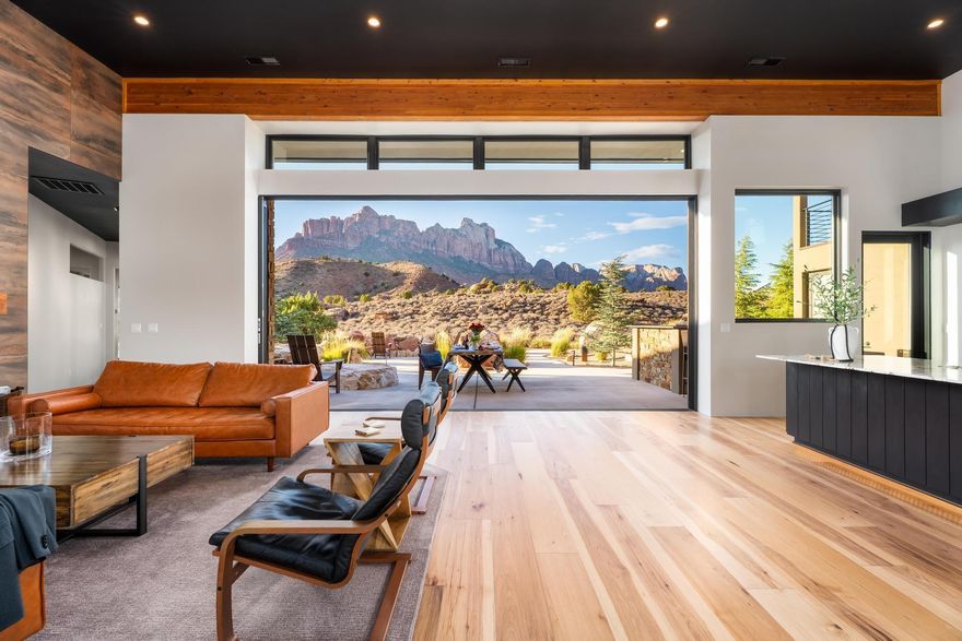 A Love Letter to the Desert :: 

Tucked high atop the Anasazi Plateau and just moments from the gates of Zion National Park, this architectural gem captures the heart and soul of the high Desert. Built in 2019, this extraordinary home is more than a residence—it's a retreat, a sanctuary, a place where timeless design meets the raw beauty of nature in perfect harmony.

Crafted in a modern desert style and wrapped in the warmth of Big Cedar timber and native stone, this home evokes the cozy romance of a mountain cabin while remaining bold, clean, and contemporary. As you approach the entry, the scent of cedar greets you—an invitation to leave the ordinary behind. Through oversized commercial glass doors, you enter a space where walls of windows dissolve boundaries and the glowing cliffs of Zion become part of the room.

Inside, a soft, neutral palette lets the landscape take center stage. Every corner has been curated for both comfort and beauty from the statement fireplace wall in the great room to the European-style kitchen adorned with high-end appliances. Here, life flows effortlessly between indoors and out. Four massive 10' sliding pocket doors open to a professionally designed outdoor terrace, where you can dine, entertain, or simply sit in stillness under Springdale's famously brilliant night sky.

Two elegant en-suite master bedrooms on the main level offer complete serenity, each with spa-like bathrooms and spacious walk-in closets. A third bedroom and bath, a designer powder room, a sleek hardwood dining table, and a cozy coat nook provide thoughtful touches throughout. Even the butler's pantry tells a story with built-in workspace, wine fridge, and function wrapped in style.

And when you step into the oversized garage, you'll find not just space for your vehicles, but a workbench, storage, and even a custom dog-wash station for your four-legged companions.
Surrounded by conservation land, this home offers unmatched privacy and silence. No rooftops. No distractions. Only the changing light on the cliffs, the stillness of dusk, the breeze through native trees. From sunrise hikes to sunset dinners, this is a place to reconnect with nature, with yourself, and with those you love.

Just minutes from Zion, and a short scenic drive to Bryce Canyon, the North Rim of the Grand Canyon, Snow Canyon, Tuacahn Amphitheatre, and the vibrant town of St. George, this home is both a private escape and a gateway to adventure.

There are homes and then there are places that live in your soul.
This is one of them.