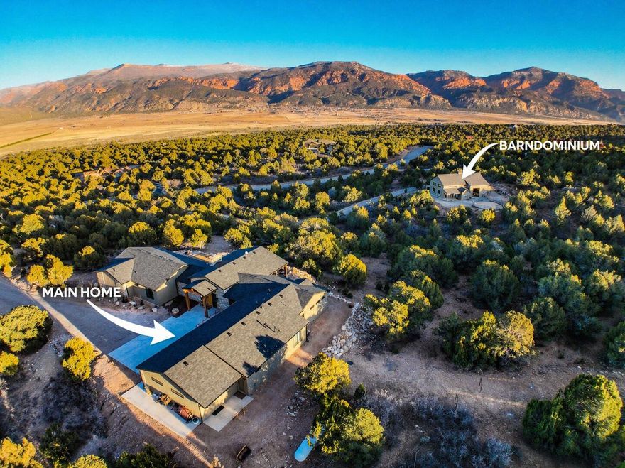 Private hilltop retreat away from the crowds. 10 miles west of Cedar and situated on 20 secluded acres, this stunning property offers panoramic views into Kolob Canyon & surrounding landscapes and is near Kanarraville and New Harmony. This beautifully designed home features 4 bedrooms/ 5 bathrooms, showcasing custom, high-end appliances & exceptional finish work throughout. Designed w/ both luxury & functionality in mind, the property includes a detached barndominium complete w/3 indoor horse stalls & an outdoor round pen, making it ideal for equestrian enthusiasts. Enough garage space w/the ability to accommodate up to 7 vehicles, including an oversized 16-ft pull through garage door.  Residents can enjoy access to the community's HOA equestrian center w/many additional amenities. Experience privacy, luxury, and scenery all in one extraordinary property.