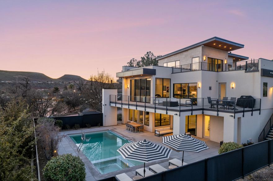 Perched two blocks above St. George Blvd and carved beneath Dixie Red Hills, this 2017 custom build brings a bold, contemporary attitude to downtown living. Set on a quiet street with authentic neighborhood character, this sleek, modern elevation makes a confident statement, blending sharp architectural lines with the soul of historic downtown. Despite its elevated, private setting, you're just a short walk from Main Street's best dining, shopping, and nightlife. Inside, the space is built for those who appreciate high-performance luxury. The chef-grade kitchen features a Sub-Zero refrigerator, Wolf appliances, and an expansive walk-in butler's pantry, made for entertaining or making everyday moments feel elevated. Control4 smart home technology runs throughout, giving you seamless control at your fingertips. The primary suite is anything but ordinary featuring his-and-her closets, a private balcony overlooking the city lights, and direct access to a hot tub for soaking in the views. Spanning three thoughtfully designed levels, each space offers privacy, perspective, and jaw-dropping, unobstructed views, making this one of downtown St. George's most distinctive residences.