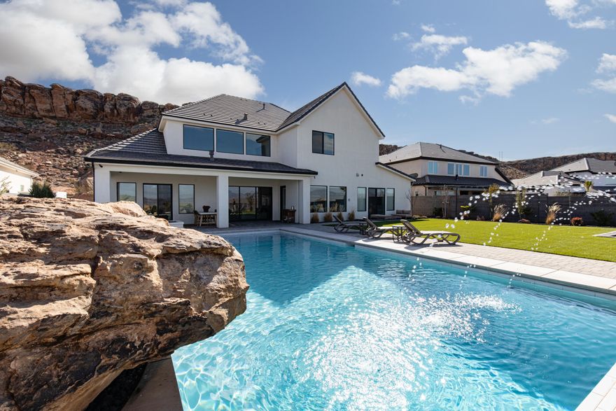 PANORAMIC VIEWS. Nearly 180° views of Pine Valley Mountain & the western half of St. George set the stage for this pristine New Trend Construction home in Little Valley. Incredible backyard, featuring a saltwater pool with natural jumping rock & motorized cover, a spacious turf area, outdoor kitchen, & built-in trampoline. Large glass doors & expansive windows throughout the home are thoughtfully positioned to capture the views, while tall doorways & ceilings enhance the sense of space & light. The home is tastefully curated with Restoration Hardware furnishings & décor, available for purchase with the home under separate agreement. The stunning kitchen showcases custom cabinetry, a built-in fridge/freezer, Monogram appliances, & upgraded designer lighting. The luxurious primary suite offers sweeping views, a walk-in shower, & custom closet. The thoughtfully designed floorplan includes two bedrooms, a dedicated living room, office, & flex room on the main level, along with a second laundry room, second family room, & bonus room. A truly one-of-a-kind property offering views, design, & functionalitythis is a home not to be missed.