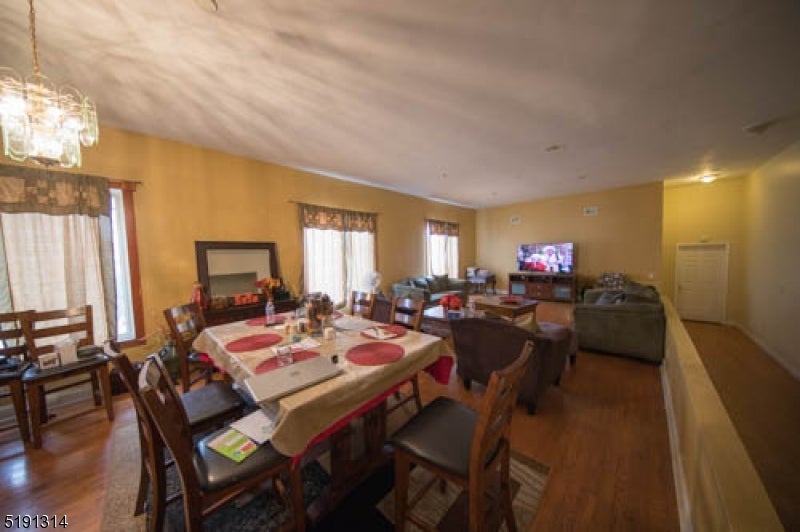 Dining and living room with a set table, wood floors, and large windows.