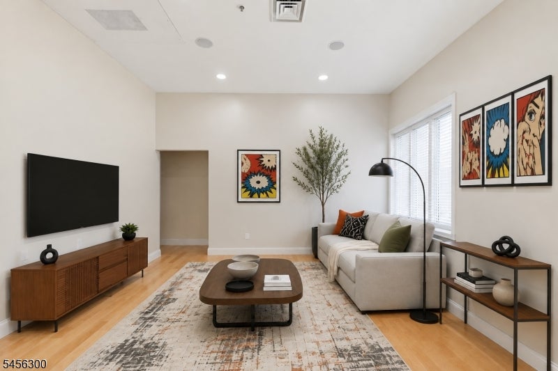 Staged living room with a white sofa, colorful pop-art prints, and a wall-mounted television.