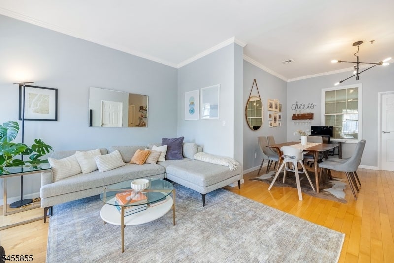 Open-plan living and dining room with a light sectional, glass coffee table, and hardwood floors.