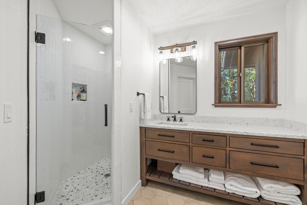 Downstairs bathroom., Wood cabinet, natural stone counters and a walk in shower. Also has access to the laundry room and mechanical room.