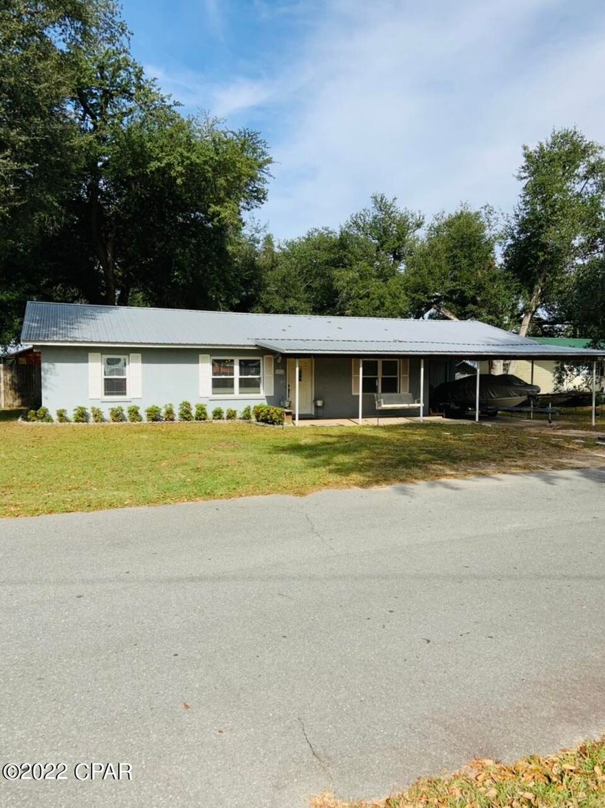 Here is a must see three bedroom, two bath home on a shaded corner lot. Home is on paved road just seconds from parks and school. Metal roof, new HVAC and many more improvements within the last 6 years.  Features a car carport as well. Back yard is fenced and gigantic Live Oaks provide the shade casting. Home is move in ready!
