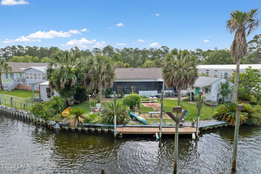 3 bedroom, 2 bath Waterfront Property on Canal, with deeded deep water boat dock that leads to Bayou Grande, and the Gulf of Mexico. Community pool and boat dry storage, and boat ramp. This home has 2 living rooms and 2 dining rooms. Gas hot water heater, gas stove and gas dryer. all appliances stay.  Shed has Electricity. Sprinkler system pump from canal. Enclosed back porch has mop/sink fish cleaning station.  Palm trees, many palm species, rose bushes and raised garden beds. Parking for 4 cars, one can be covered. Short term rentals are allowed. A boaters/fisherperson's oasis. Live in it, or make it your new Rental. Close to the Naval Air Station, see the Blue Angels up close. Centrally located in a great neighborhood. This is an older mobile home, due to the age it is ''CASH ONLY'' and is being sold ''As Is.''  Come see, and make an offer, seller is packed and ready to go!