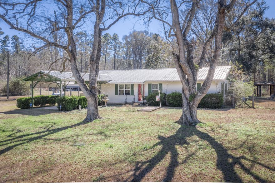 Situated in a private, country setting sits this cozy 2/1 . Home has living room and a separate den area that could easily be converted into a 3rd bedroom, if desired. Open floor plan with kitchen and dining area with access to a bonus room that is currently being used as a home office. Bathroom has been updated to include a Premier walk-in tub/shower. Vinyl (with wood look) flooring can be found thru-out most of home. Oversized master bedroom is complete with 2 walk in closets. Updated double pane windows along with newer metal roof. Outside boasts attached one car carport, detached metal oversized carport, circular drive, pond and lots of room for storage in the yard buildings/barn. Home is also complete with a full house Generac gas Generator and BONUS "Man Cave" metal building that has electricity and a window unit.  All of this and more sitting on 8 acres.  Don't miss out, call for your viewing today!