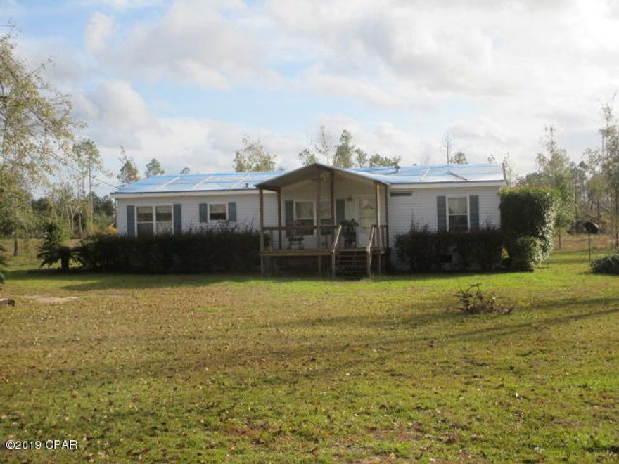 $79,500. CONTRACT PENDING. This 1991 double-wide with 1,568 sq. ft. of living space sits on 5.12 acres of open, level land, with road frontage on two sides. The home suffered some roof damage during Hurricane Michael but is tarped and livable in it's present condition, until the roof can be replaced. All damaged trees were removed, the land root-raked, and the stumps removed. Owners are selling the home ''as-is'' so a buyer seeking financing may need to get a rehab or renovation loan to cover the repair cost for the roof and other minor damage. The 3BR/2 bath double-wide has electric central heat and air (outside package unit); inside unit is not connected but could be converted to a closet; Frigidaire side-by-side refrigerator/freezer; a Frigidaire glass cooktop stove with oven; carpet in LR, DR, and MBR, and vinyl flooring in the remainder of the home. Property has a deep well, septic tank, and a 16' x 24' shed/workshop with power and water. The open 5+ acres is in Flood Zone X, with corners flagged. Owner also reports that there are French drains in the yard but they may need some work. Deer tracks can be seen all around on the 5+ acres as you walk out in the field! Located only 3-4 miles from Wewahitchka for groceries, gas, school, etc., and about 25 miles from Mexico Beach. $79,500.
