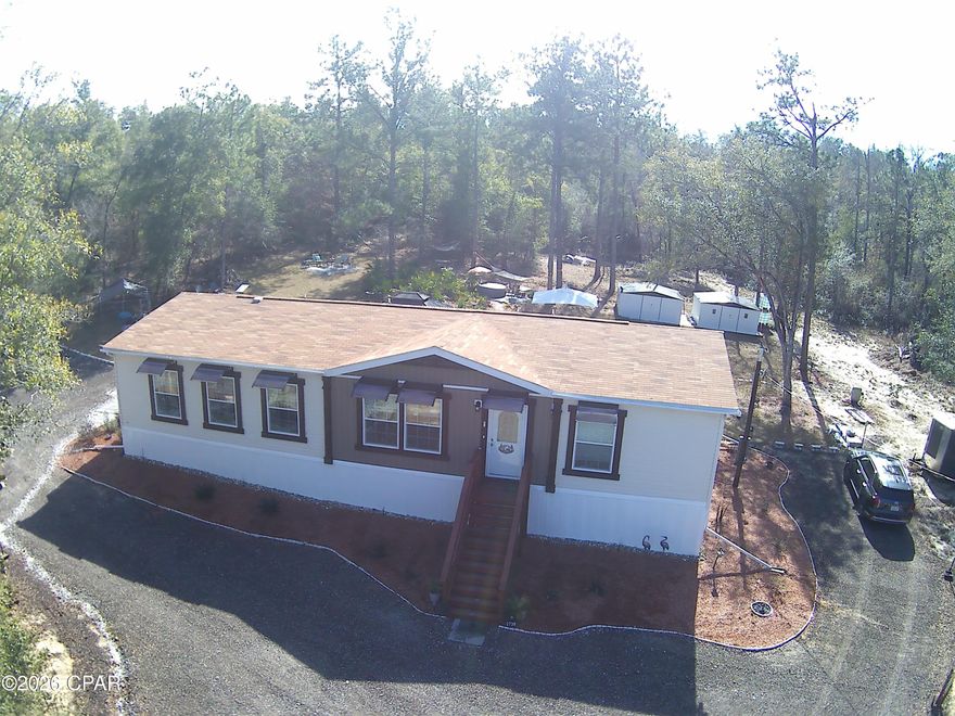 Located in the Compass Lake in the Hills resort community, this recently built, like-new home (completed less than one year ago) offers a rare blend of new construction and fully developed outdoor living on 2.02 high-and-dry acres tucked away on a quiet cul-de-sac.
The thoughtfully designed 1,780-square-foot, 3-bedroom, 2-bath home features a spacious open layout with a large kitchen and center island, generous living area.  In addition to the standard smoke detectors.  Photo electric smoke detectors have been installed.  Filtration systems have been installed underneath all sinks.   Seamless flow to the outdoors—ideal for both everyday living and entertaining. The home is serviced by a private well drawing from Florida's natural aquifer system, providing a reliable, independent water supply. For added peace of mind, the property is equipped with perimeter security cameras, motion sensors, and wildlife/game cameras, offering enhanced safety and situational awareness throughout the grounds.
Outside, the property truly shines as a private retreat-style compound. A short distance shooting range equipped with four shooting benches.  A fully equipped outdoor kitchen under a 12×12 metal pavilion includes stainless steel prep tables, grill, griddle, four-burner stove, gas pizza oven, and stainless sink—designed for serious outdoor cooking and year-round gatherings. Multiple outdoor living zones include a hot tub area surrounded by native palmetto and three separate smokeless fire pit areas, creating comfortable, low-smoke spaces for relaxation and entertaining.
Nature lovers will appreciate the walking and nature trails winding through the wooded acreage, along with established centipede sod, mature pine, and native landscaping. The grounds also feature established fruit trees including banana, fig, pomegranate, and orange, plus an 8×12 greenhouse and a large fenced garden with 24 blueberry bushes, offering a productive and well-planned growing space.
Additional improvements include a new 16×24 detached cabin ideal for guests, studio, or flex use; two 12×14 metal storage sheds; three 24×20 covered carports for vehicles, boats, or recreational equipment; and a covered 10×10 outdoor dog kennel. A level, fenced recreational area is currently configured for low-impact .22 caliber and air rifle use with four shooting tables and lanes, and can easily be repurposed into a corral or paddock for mini horses or other animals. The backyard is also pool-ready, allowing the buyer to select their preferred design.
This property offers the peace of mind of a newer home combined with the luxury of fully finished land, extensive outdoor amenities, flexible spaces, modern security features, and independent utilities—elements rarely found together at this price point—making it ideal for full-time living, a second home, or a private Florida retreat. Some photos were provided by the seller.