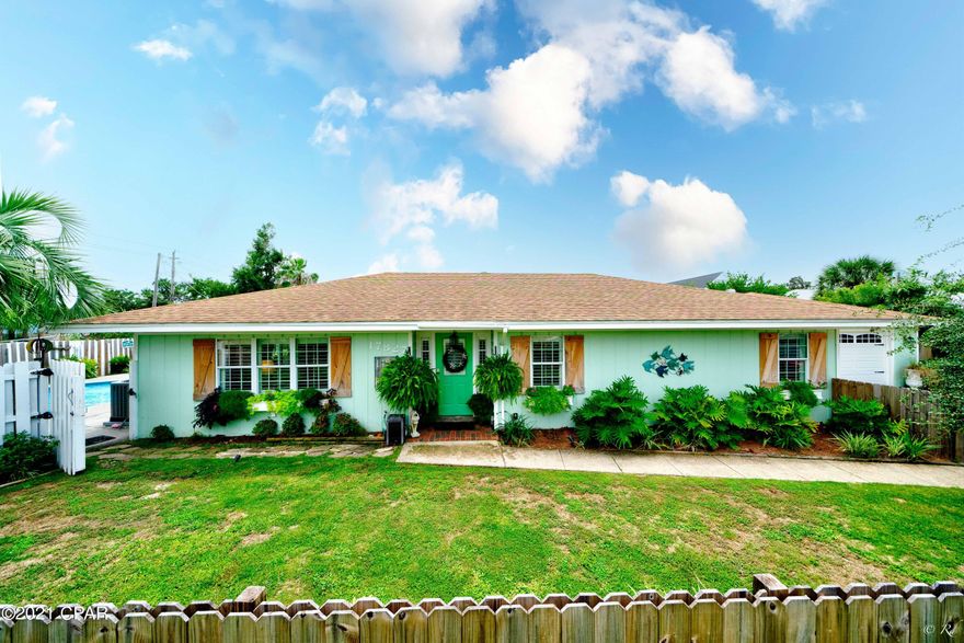 Stunning 3 bed, 2 bath home with a detached MIL suite and saltwater pool located on a corner lot just blocks from the beach. This property will wow you from the moment you arrive! The front yard is landscaped and adorned with a double-sided privacy fence, palm trees and pampas grass bushes. The windows are equipped with planters and plantation shutters along with plantation blinds throughout the home.  Wood-look tile throughout the home provides the durability of tile with the modern look of LVP. This home welcomes with an inviting foyer. The open living room, dining area and kitchen boasts beautiful bullnose arches. The open floor plan offers a grand spot to host family and friends without missing a beat. The kitchen features stainless appliances including a double door refrigerator with a double drawer freezer, granite counters, a breakfast bar and a large pantry. The kitchen/dining area is also equipped with a wine cooler along with a wet bar for the ultimate hosting convenience. The spacious master bedroom features a double mirrored closet and a private en suite. The master bathroom features a new vanity and a surround-tile shower with a glass door. Double doors off the master suite lead to the back patio. There are 2 guest bedrooms that feature herringbone design floors and they share a full guest bathroom. The guest bathroom features a new vanity and a shower/tub combo. Double doors off the dining area lead to your private oasis out back! The backyard is breathtaking with a salt water pool, palm trees, fountain, covered patio and more. The covered patio boasts two ceiling fans, herringbone designed floors and a TV plug. The spacious MIL suite features a studio floor plan with an open living area, bedroom and kitchenette. There is a full bathroom with a walk-in shower and new vanity. This home is just a short walk to the white sandy beaches and a short drive to 30A and Pier Park.