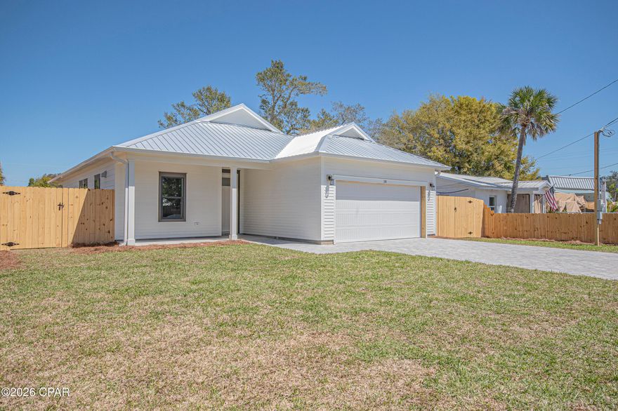 Step into this semi-custom home beautifully designed with plenty of upgrades. Let's start outside. This home greets you with hardi siding, impact windows and doors, metal roof (all for discounted insurance rates), cornered back patio, sodded yard with irrigation, privacy fenced back yard, and paver driveway round out the outside. As for the inside, let's start with the kitchen, white shaker style cabinets with crown molding, built-in microwave in island, a gas stove with stainless steel vent hood (venting to the outside), full-size refrigerator with water & ice in the door, dishwasher, garbage disposal, all under gorgeous quartz countertops. Moving on, all 8 foot doors and  plank vinyl flooring throughout the home as well as 9/10 foot ceilings. Plenty of can lights as well as upgraded light fixtures. The living room features a tray ceiling and an electric fireplace, Now for the master bedroom, which features its own tray ceiling with fan and can lights. Master bath has a double bowl vanity with quartz top. Master shower is 4'x5', tiled with bench to relax on. All closets and pantry have wood shelving. Energy wise, the home features all spray foam in walls and attic, and a gas tankless water heater providing endless hot water. Home is 2 minutes to Tyndall Air Force Base, 3 minutes to Bay Oaks Park (a beautiful park on the bay), and 5 minutes to shopping. Put this home on your short list.