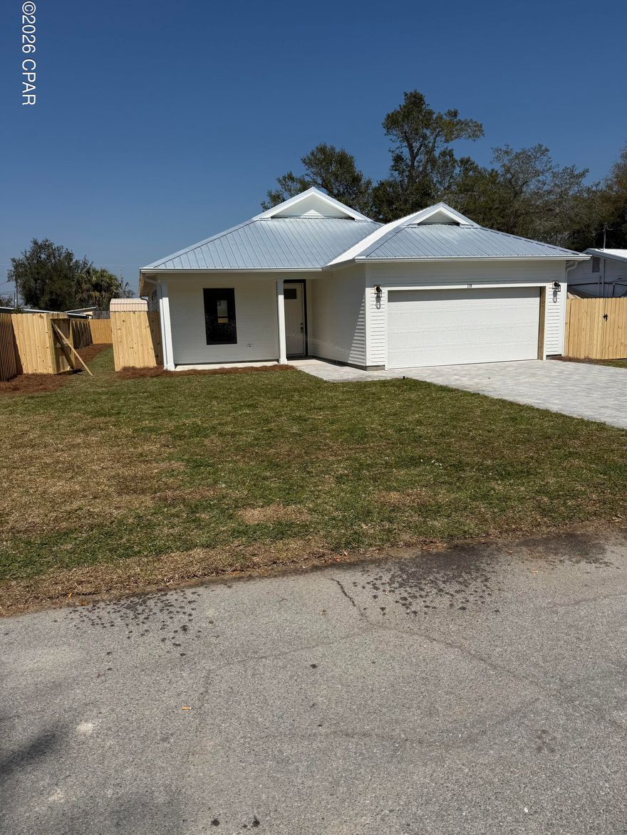 Step into this semi-custom home beautifully designed with plenty of upgrades. Let's start outside. This home greets you with hardi siding, impact windows and doors, metal roof (all for discounted insurance rates), cornered back patio, sodded yard with irrigation, privacy fenced back yard, and paver driveway round out the outside. As for the inside, let's start with the kitchen, white shaker style cabinets with crown molding, built-in microwave in island, a gas stove with stainless steel vent hood (venting to the outside), full-size refrigerator with water & ice in the door, dishwasher, garbage disposal, all under gorgeous quartz countertops. Moving on, all 8 foot doors and  plank vinyl flooring throughout the home as well as 9/10 foot ceilings. Plenty of can lights as well as upgraded light fixtures. The living room features a tray ceiling and an electric fireplace, Now for the master bedroom, which features its own tray ceiling with fan and can lights. Master bath has a double bowl vanity with quartz top. Master shower is 4'x5', tiled with bench to relax on. All closets and pantry have wood shelving. Energy wise, the home features all spray foam in walls and attic, and a gas tankless water heater providing endless hot water. Home is 2 minutes to Tyndall Air Force Base, 3 minutes to Bay Oaks Park (a beautiful park on the bay), and 5 minutes to shopping. Put this home on your short list.