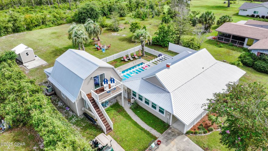 PRIVATE MULTI-GENERATIONAL BEACH LIVING, 2 SEPARATE HOMES, JETTED POOL with GULF VIEW. Beach Oasis designed for multi-family / multi-generational living. Located on a private 0.64-acre lot (X flood zone), backing to 82 acres of preserved land, this rare property delivers serene seclusion, a jetted pool courtyard, and views of the Gulf - all just 300 steps to the beach!!  With two separate homes, everyone can spread out and still stay connected--perfect for extended family, guests, or investor rental potential.  Main Home (2BR/1BA):   Step into a calm coastal retreat featuring a cozy brick wood-burning fireplace and a renovated kitchen with warm pecky cypress accents. French doors open to a spacious entertainment/sunroom with vaulted ceilings and 8 panoramic windows framing beautiful sunset views. Start your day or unwind at dusk, listening to the Gulf waves crash on the 50-foot front porch - a true lifestyle feature.  Guest Cottage (2-story, 2BR/2BA):  Just beyond the pool courtyard, the guest cottage offers its own boho beach vibe and comes fully furnished as a turnkey rental opportunity. Enjoy a second-floor deck with a Gulf view, plus a home theater featuring an 82'' TV. The second floor includes a queen sleeper sofa and has a private entrance, making it ideal for an owner's suite.  Enjoy $100K+ in improvements and extras, including a fully furnished Guest Cottage, $15K in hurricane windows, a golf cart, 2 kayaks, 7 mounted TVs and more!!  Welcome to private coastal living with space and flexibility!!