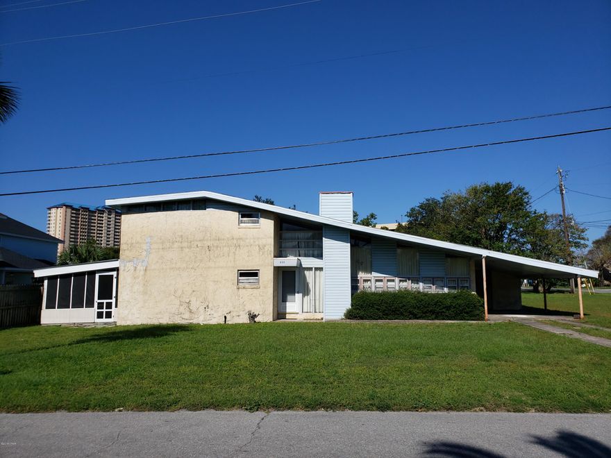 Don't miss this vintage contemporary mid century home with its open spaces and prefect location. It is located on a corner lot in the Open Sands neighborhood and is less than a ½ mile to the beautiful white sandy beaches of the Emerald Coast. It is also convenient to Pier Park with lots of shopping and restaurants. The oversized living area features a dramatic vaulted ceiling, modern fireplace, an open staircase that leads to the loft area leading to 3 bedrooms and a full bath. The kitchen is open into a large family room and both open onto a large screened porch on the Gulf side to catch those wonderful ocean breezes.  This is a large lot with lots of possibilities.  Bring your best offer!   Ver