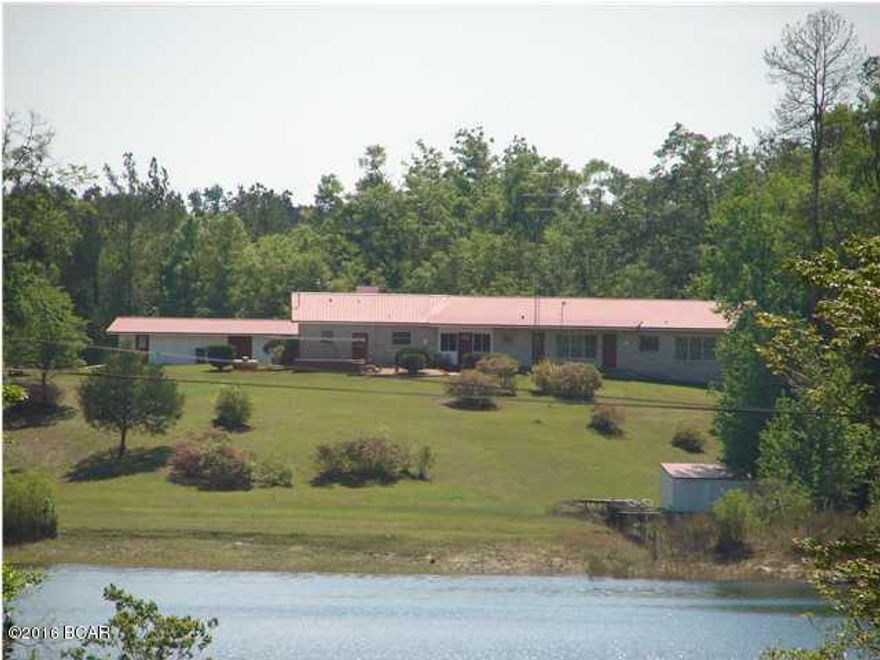 Spacious WATERFRONT home situated on 5.11 acres on beautiful White Pond in Altha. This lake is approximately 25 acres and allows electric powered boats, sailboats, canoes, etc. No gas powered boats. This impressive home has a full 1 bedroom/1 bath apartment at one end (complete with kitchen and living areas) and 2 bedroom/2 bath home at the other(also with kitchen and living areas), connected by a large family/ game room. Other features include: 2 wells, 2 septics, newer metal roof, 2 kitchens, broken quarry tile in living area, Culligan water purifier, cedar lined closets, boathouse with dock, 1 car garage & workshop, and fenced yard. The acreage and water view are absolutely stunning. Don't let another summer pass without fulfilling that dream of owning a lakefront getaway!